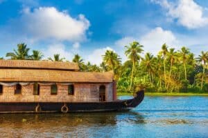 Casa galleggiante tradizionale sulle lagune del Kerala, circondata da palme da cocco.