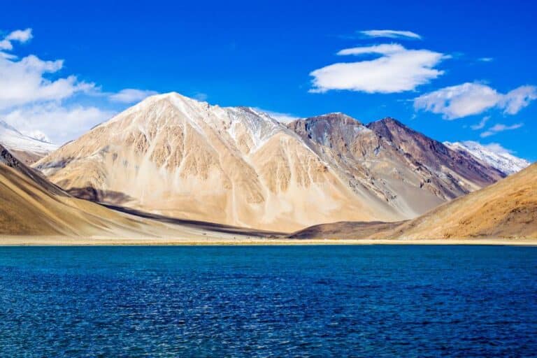 Panoramic view of Pangong Tso lake with blue water and Himalayan mountains during a private Leh Ladakh trip package